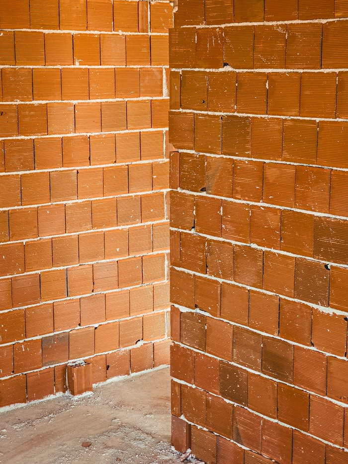 Close-up of an unfinished red brick wall corner in a construction site.