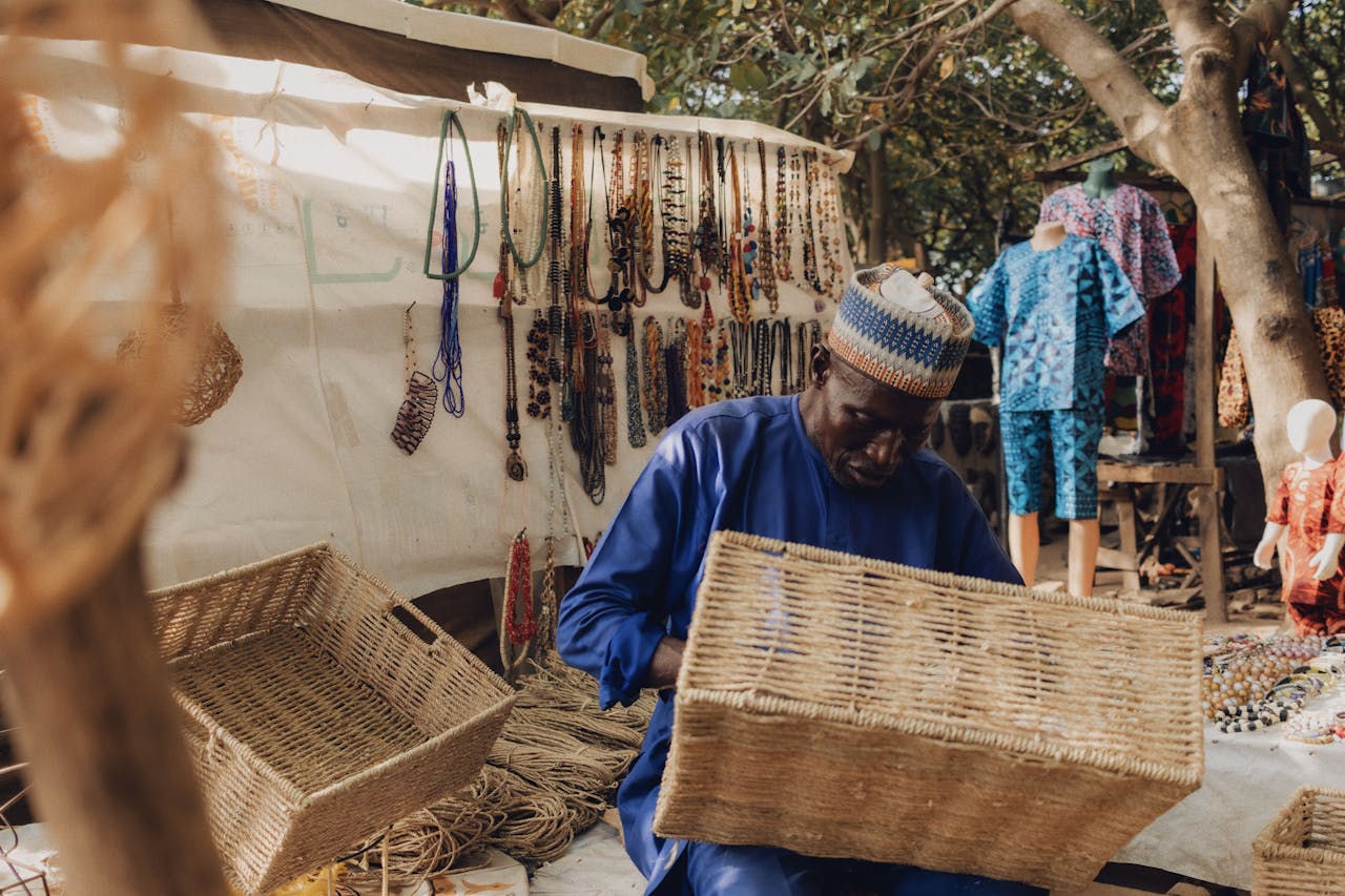 African artisan weaving baskets in a vibrant Nigerian outdoor market.