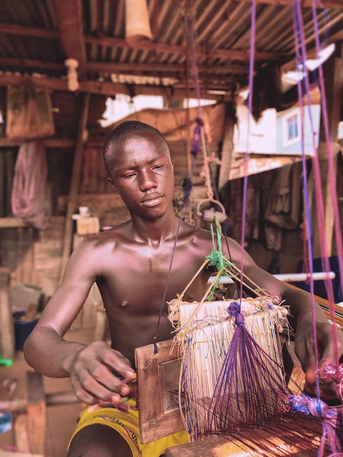 Portrait of a man weaving using traditional methods in a rustic setting, showcasing cultural heritage.